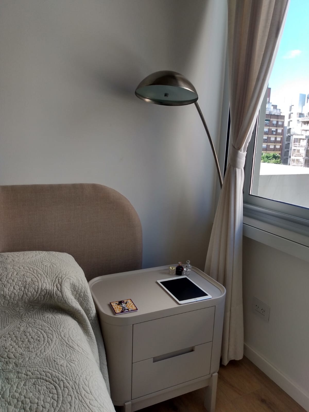 Dormitorio con respaldo tapizado y cortinas